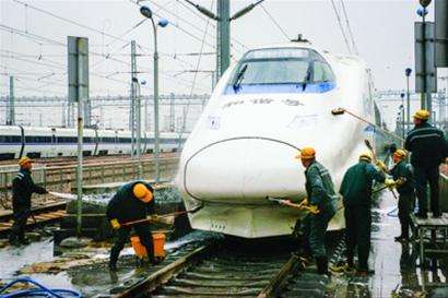 清洗工人在雨天對(duì)剛返回的車體進(jìn)行清洗，保證車輛外觀干凈，機(jī)車安全運(yùn)行。